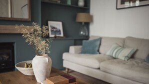 A living room with a wooden coffee table, a white vase with dried flowers, and a stack of books. - Fairhaven (Dartmouth)