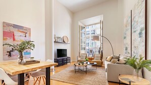 A modern living room with a wooden dining table, a sofa, and a TV. - Wonderful 1-bedroom apartment in Malaga center. San Agustin I (Malaga)