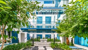 A modern building with a blue facade, surrounded by a garden with stepping stones and various plants. - Wonderful 1-bedroom apartment in Malaga center. San Agustin I (Malaga)