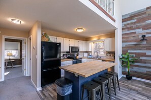A modern kitchen with a central island, stainless steel appliances, and a wooden accent wall.