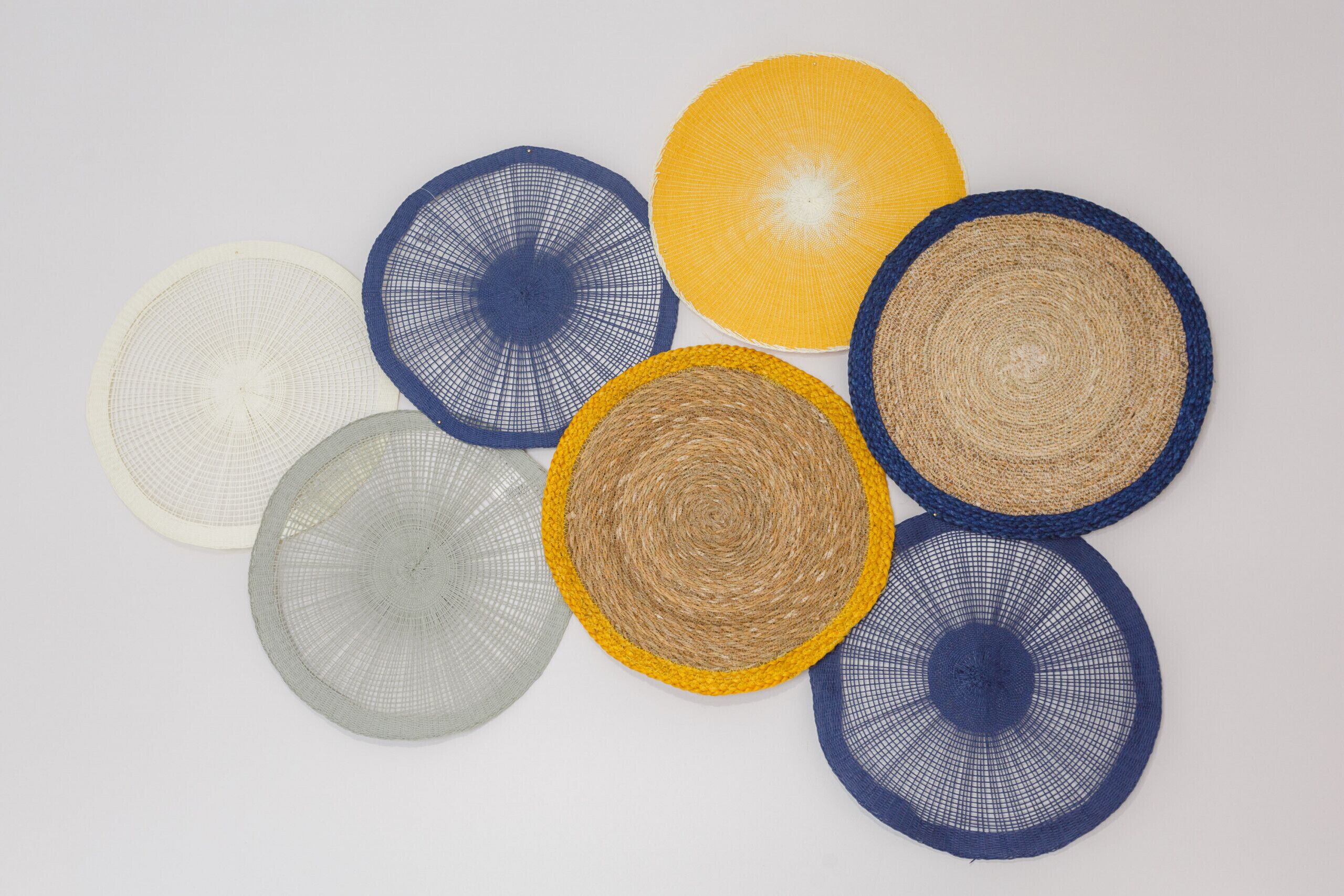 A collection of circular woven mats in various colors and patterns.