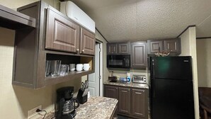 A compact kitchen with dark wooden cabinets, a black refrigerator, a microwave, and a toaster.