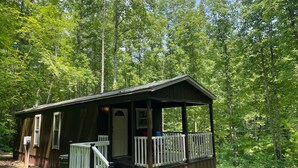 A cabin with a porch, surrounded by dense forest.