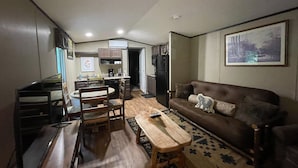 A compact living space with a dining area, a sofa, and a kitchen in the background.