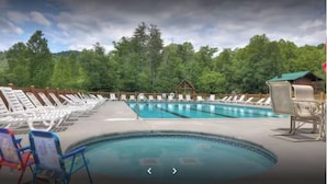 A swimming pool with lounge chairs and a barbecue area, surrounded by trees. - Moonlight Cottage - Romantic Smoky Mountain Cabin with Hot Tub & Community Pool (Sevierville)