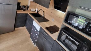 A modern kitchen with a stainless steel refrigerator, a built-in dishwasher, a microwave, and a stove. - 45 m2 FULLY RENOVATED APARTMENT IN THE HEART OF THE ANGLES 4/6 BEDROOMS (Les Angles)