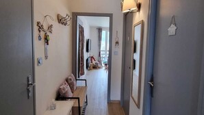 A narrow hallway with a wooden bench, a small table, and a dog. There are doors on both sides and a lamp on the right wall. - 45 m2 FULLY RENOVATED APARTMENT IN THE HEART OF THE ANGLES 4/6 BEDROOMS (Les Angles)