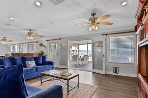 A spacious living room with a blue sofa, a coffee table, and a ceiling fan. - Peaceful Island Retreat - Heated Pool - Sleeps 10 (Jacksonville)