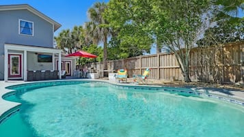 Relax by the pool surrounded by a patio area with a table and chairs.