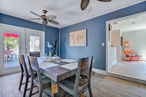 Un comedor con una mesa, sillas, un ventilador de techo y un mapa del mundo en la pared.