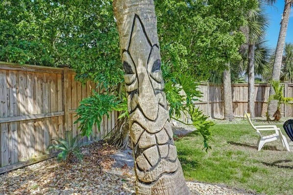 Un jardin avec une clôture en bois, un palmier et une chaise.