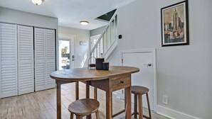 Une cuisine avec une table en bois, des tabourets, un escalier et une porte.