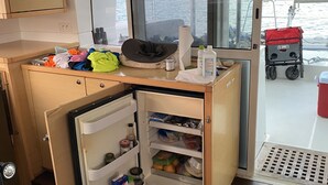 Una cocina compacta con refrigerador, una pequeña encimera y ventana con vista al agua.