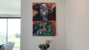 A modern living room with a large window, a sofa, a coffee table, and a decorative painting on the wall. - LA Petite Terrasse Lavoisier (La Rochelle)