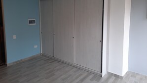 Una habitación con un gran ventanal corredero, paredes azul claro y piso de baldosas grises.