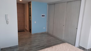 Un pasillo con un armario de madera, pared azul y suelo gris.