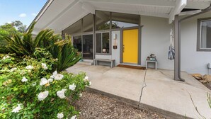 A modern house with a covered porch, large windows, and a yellow door.
