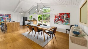 A spacious kitchen with a dining area, wooden flooring, and large windows.