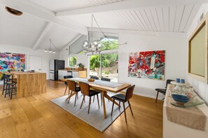 A spacious kitchen with a dining area, wooden flooring, and large windows.