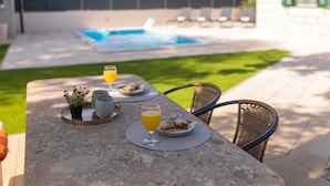 A dining table with plates of food, a glass of juice, and a potted plant.