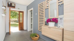 A hallway with a wooden cabinet, a mirror, and a basket with plants.
