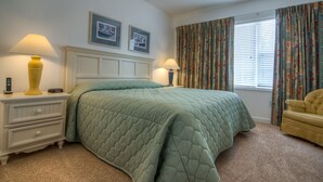 Un dormitorio con cama, mesitas de noche, lámpara, silla y ventilador de techo.