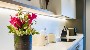 Een moderne keuken met een wit aanrecht, een bloevas en een schilderij aan de muur.