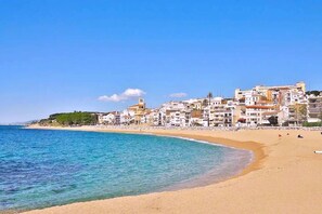 A coastal town with buildings along the beach, clear blue water, and a sandy shoreline. - Fantastic Beachfront Villa With Private Garden (Sant Pol de Mar)