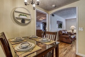 Cozy dining area with a wooden table, comfortable sofa, and a round mirror.