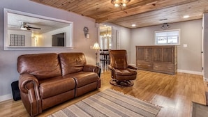 Un salon avec un canapé en cuir marron, un fauteuil en cuir et un plafond en bois.