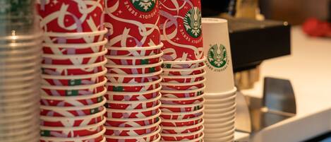 Pilhas de copos Starbucks e uma máquina de café em uma bancada.