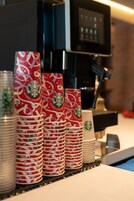 Varias tazas de Starbucks y una máquina de café sobre una barra.