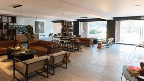 Un vestíbulo amplio con sofás de cuero, una zona de bar y un ventanal con vistas al exterior.