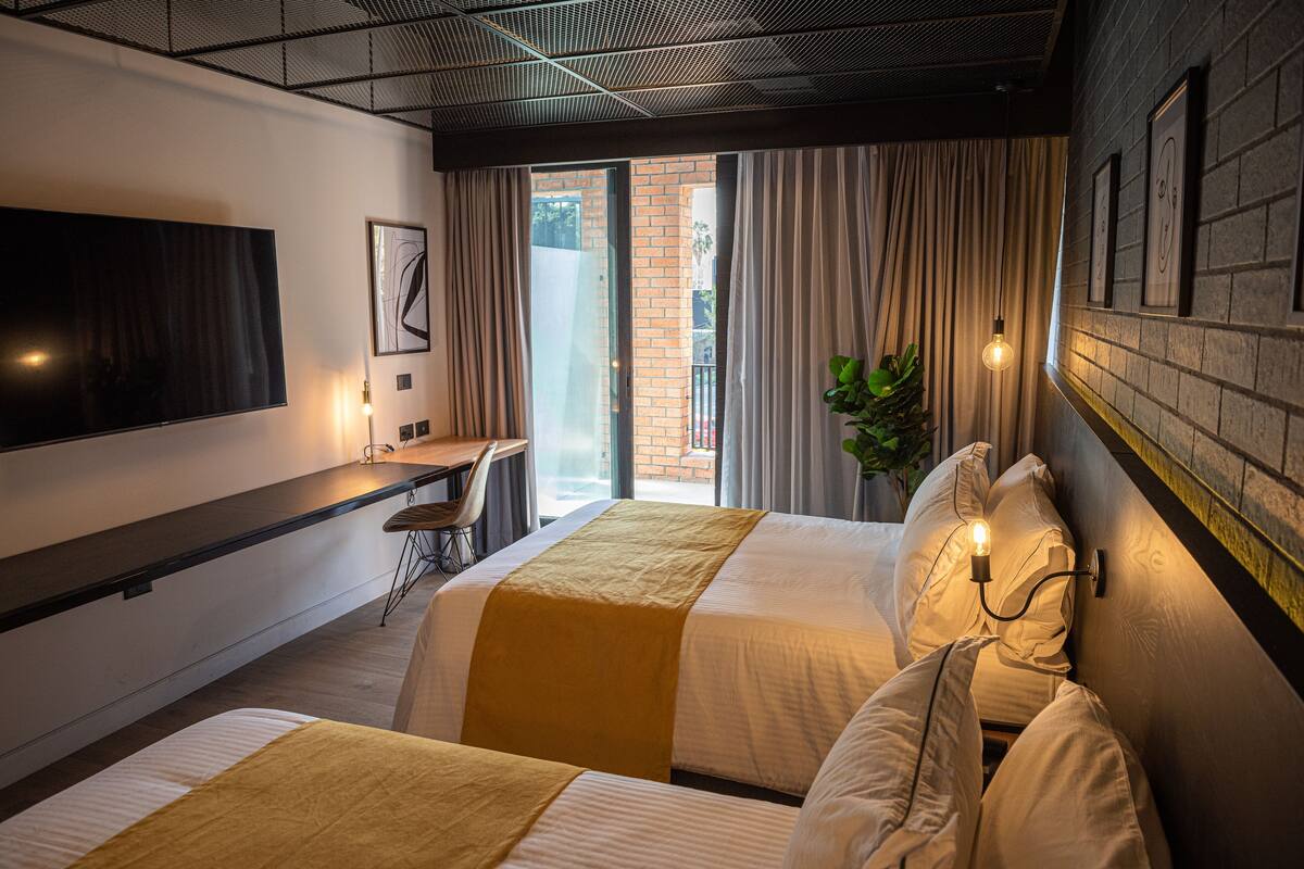 Una habitació d'hotel amb dos llits, un escriptori i una televisió.