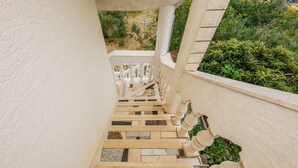 Eine Treppe mit weißer Balustrade, Steinstufen und Blick auf Grünfläche.