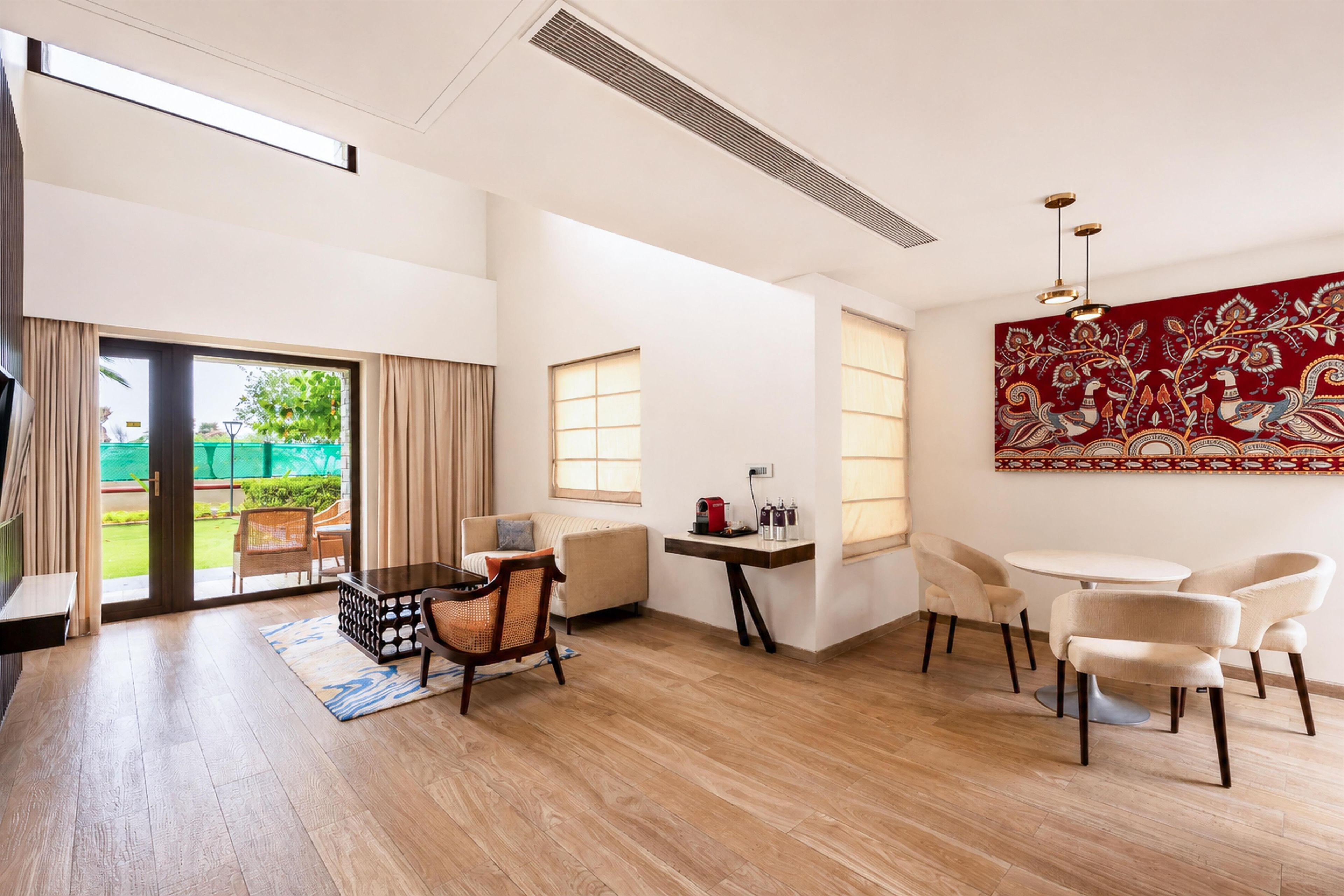 A spacious living area with a dining table, chairs, a sofa, and a coffee machine.