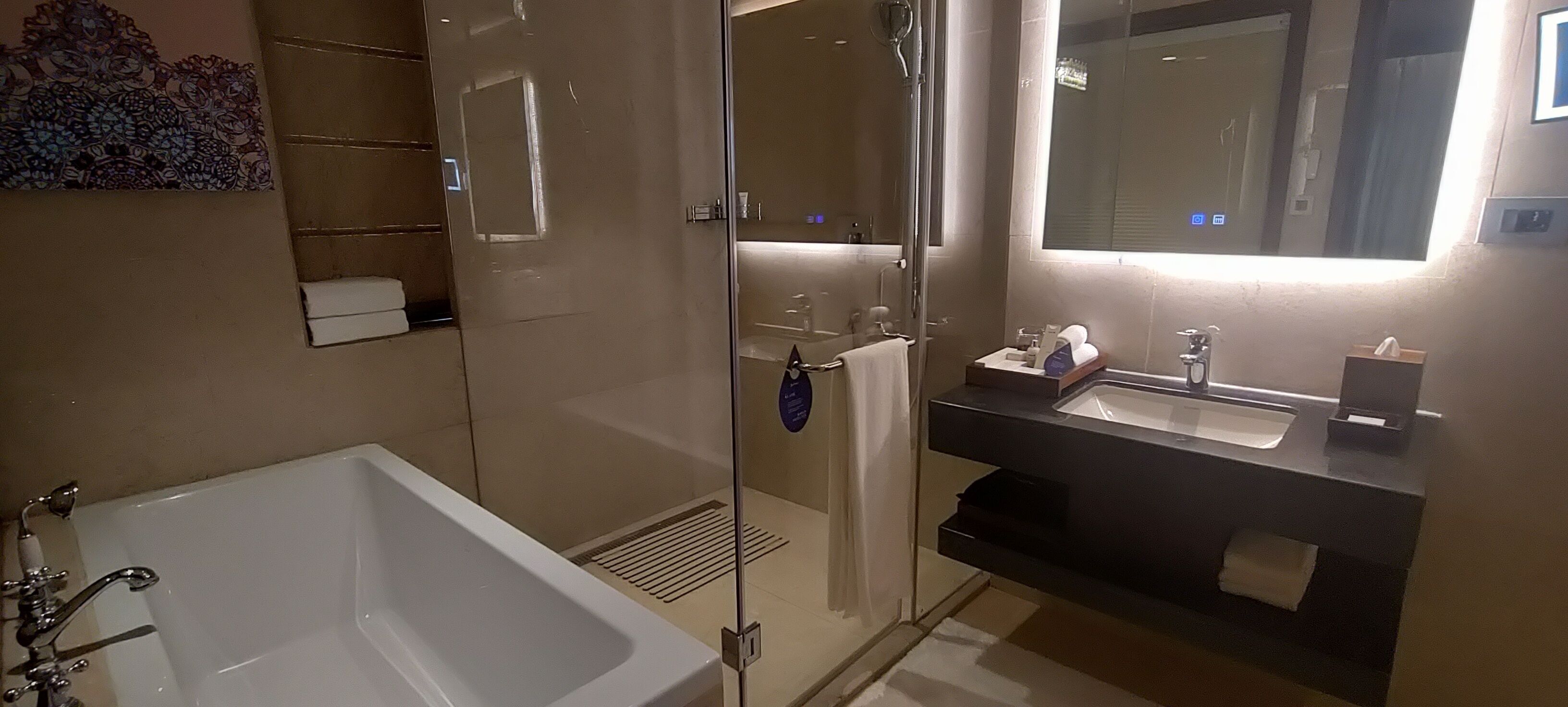Ein modernes Badezimmer mit einer Duschkabine, einer weißen Badewanne und einem Waschtisch mit Spiegel.