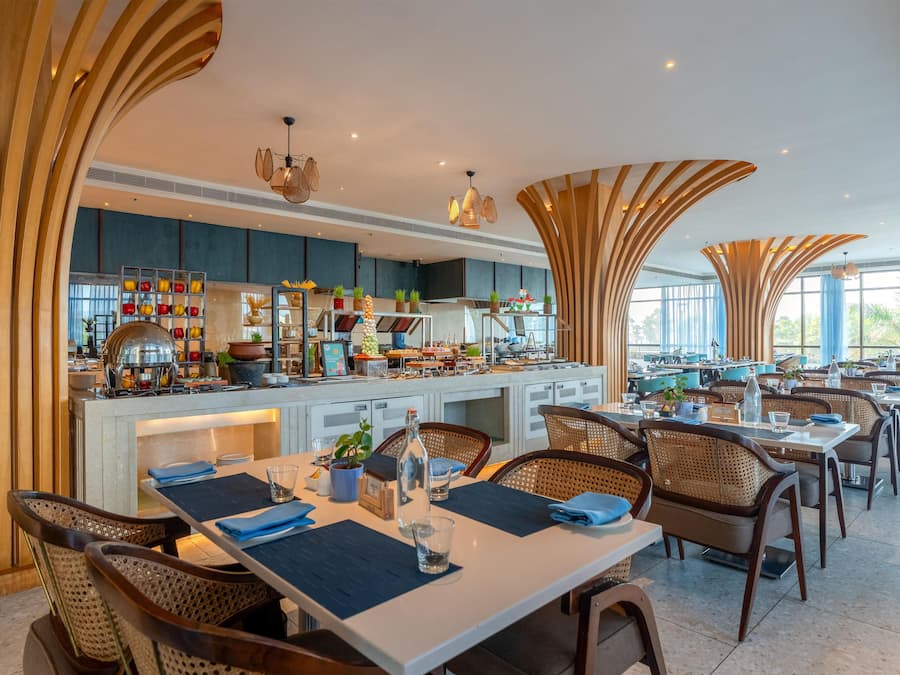 Un restaurant moderne avec de hauts plafonds, un bar central et une salle à manger avec des tables et des chaises.