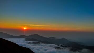 A mountain landscape at sunrise with clouds below the peaks.