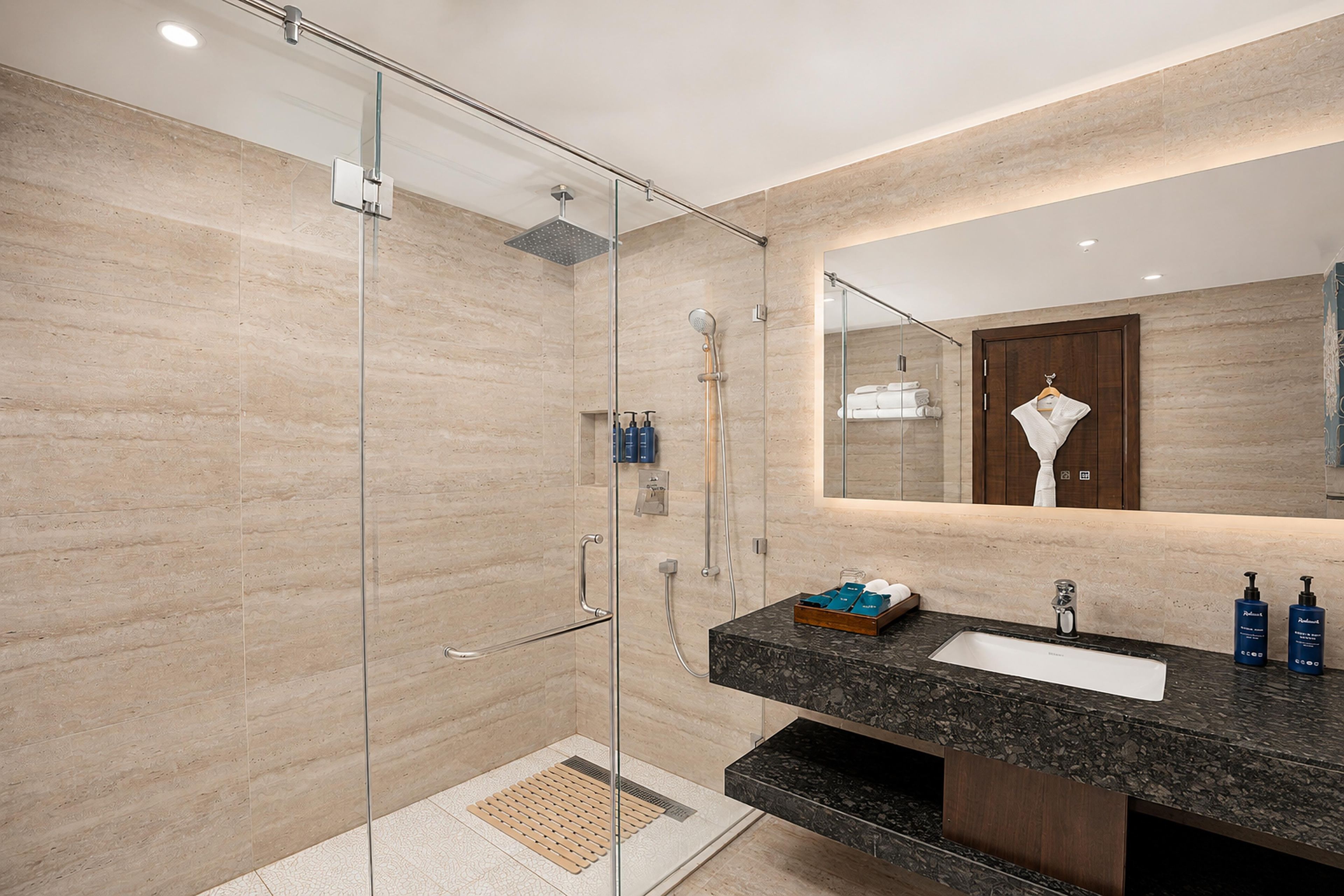 A modern bathroom with a glass-enclosed shower, a marble sink, and a large mirror.
