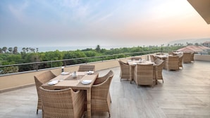 Eine Dachterrasse mit Korbmöbeln und Meerblick.
