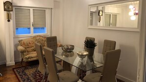 Un comedor con una mesa de vidrio, cuatro sillas, un cuenco decorativo y una planta en maceta.