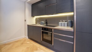 A modern kitchen with dark cabinetry, a built-in oven, a sink, and a toaster.