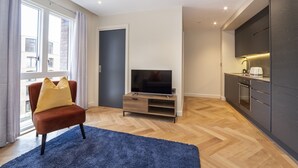 A modern living room with a TV, a sofa, and a kitchen area. - Apartment 28 Hudson Quarter Luxury Apartments - sleeps 4 guests  in 1 bedroom (York)