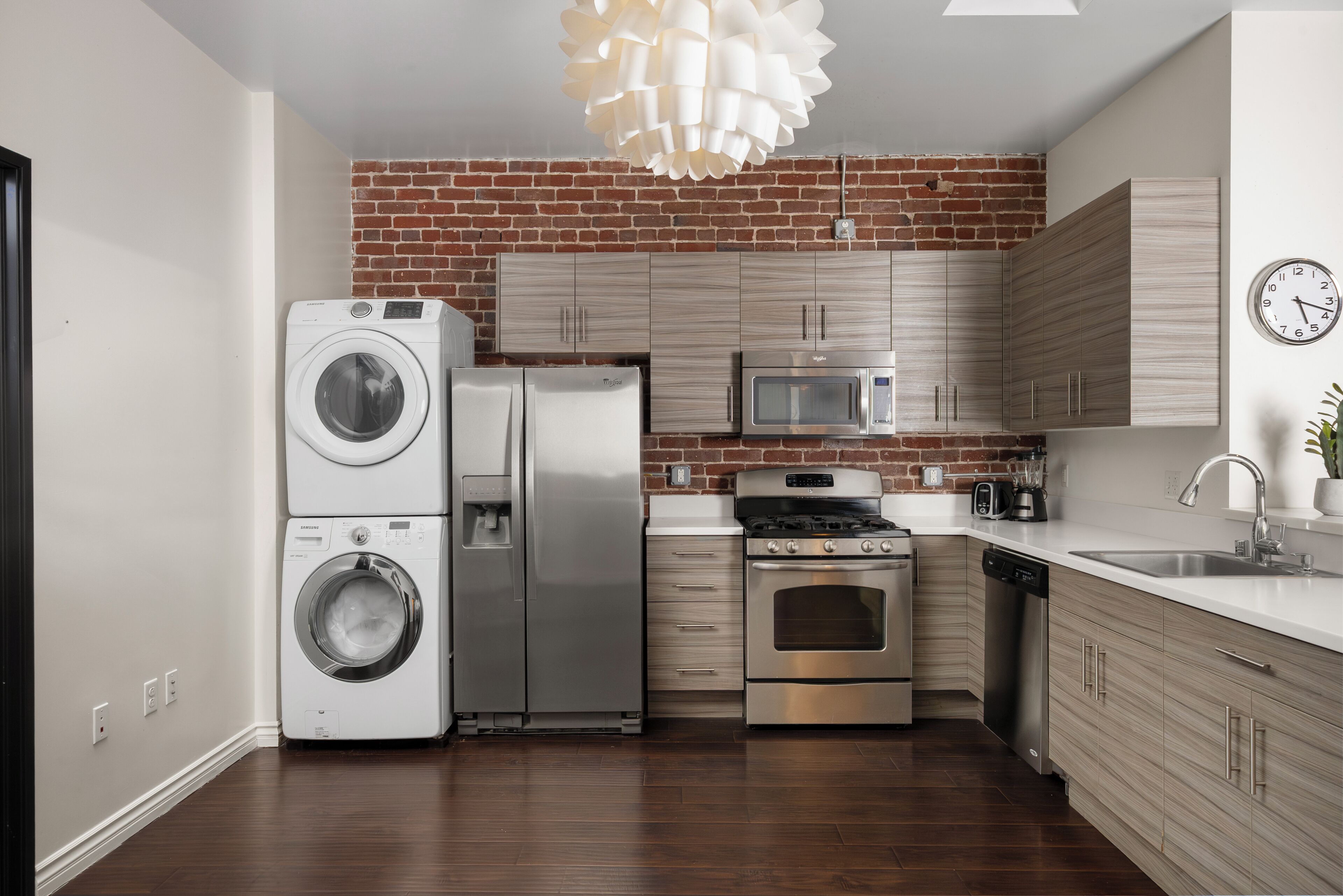 Een moderne keuken met een bakstenen muur, roestvrijstalen apparatuur en houten keukenkastjes.