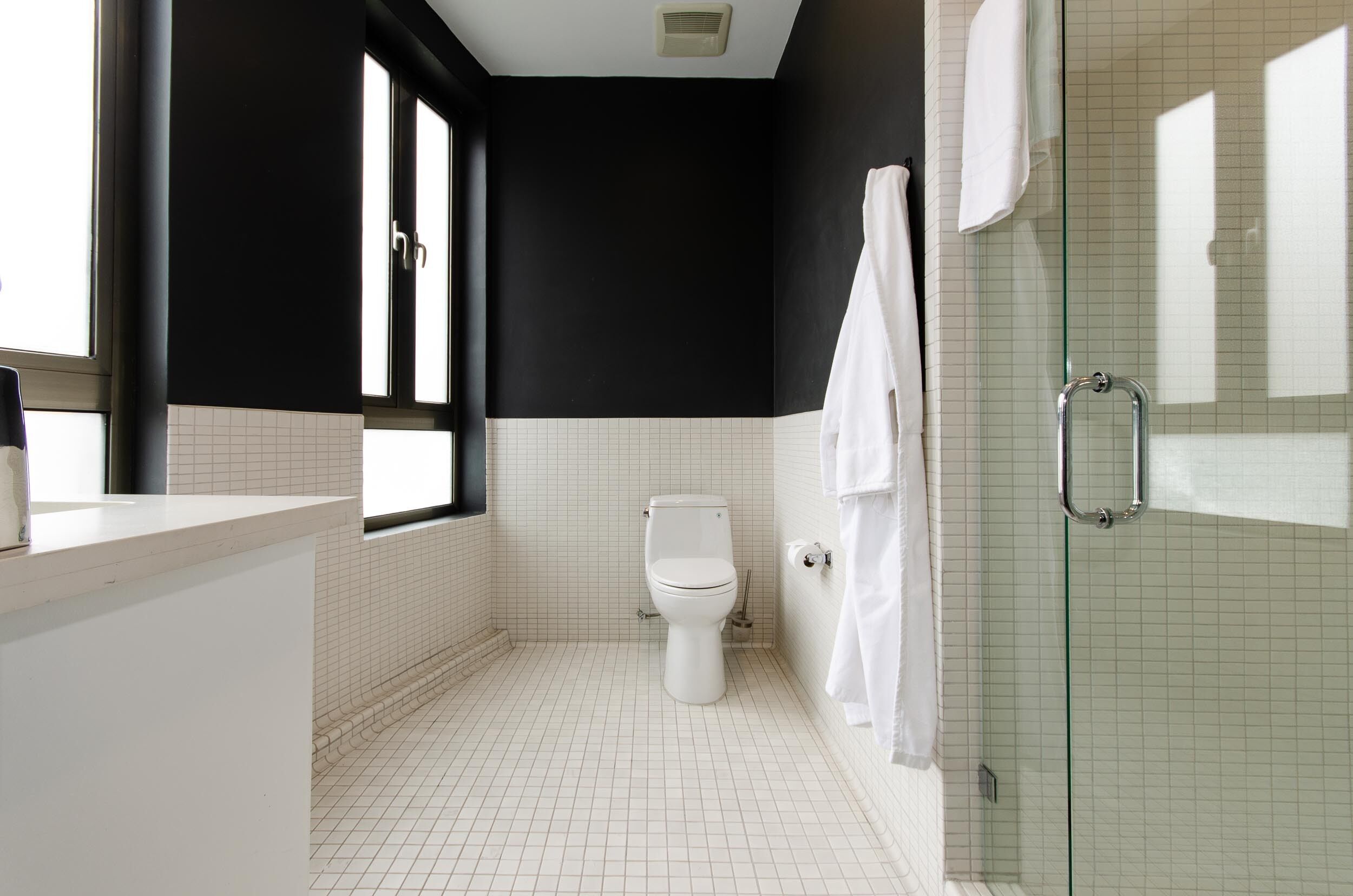 A bathroom with a toilet, a glass shower enclosure, and a white sink.