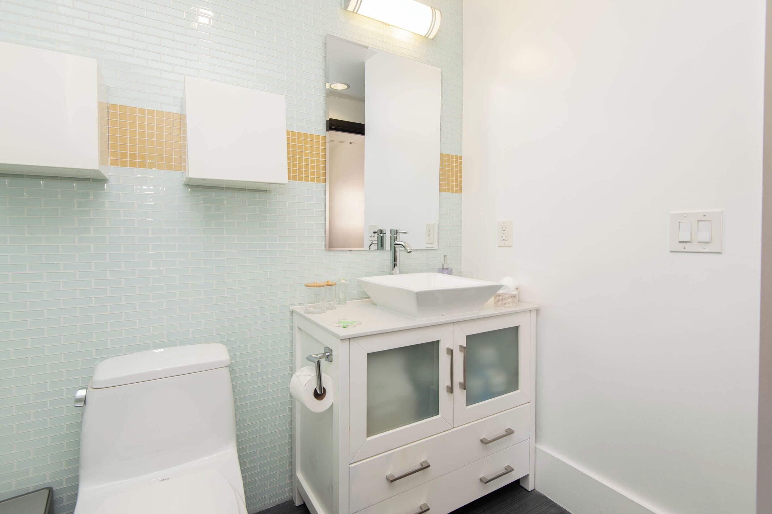 A bathroom with a toilet, a sink with a mirror, and a cabinet with drawers.