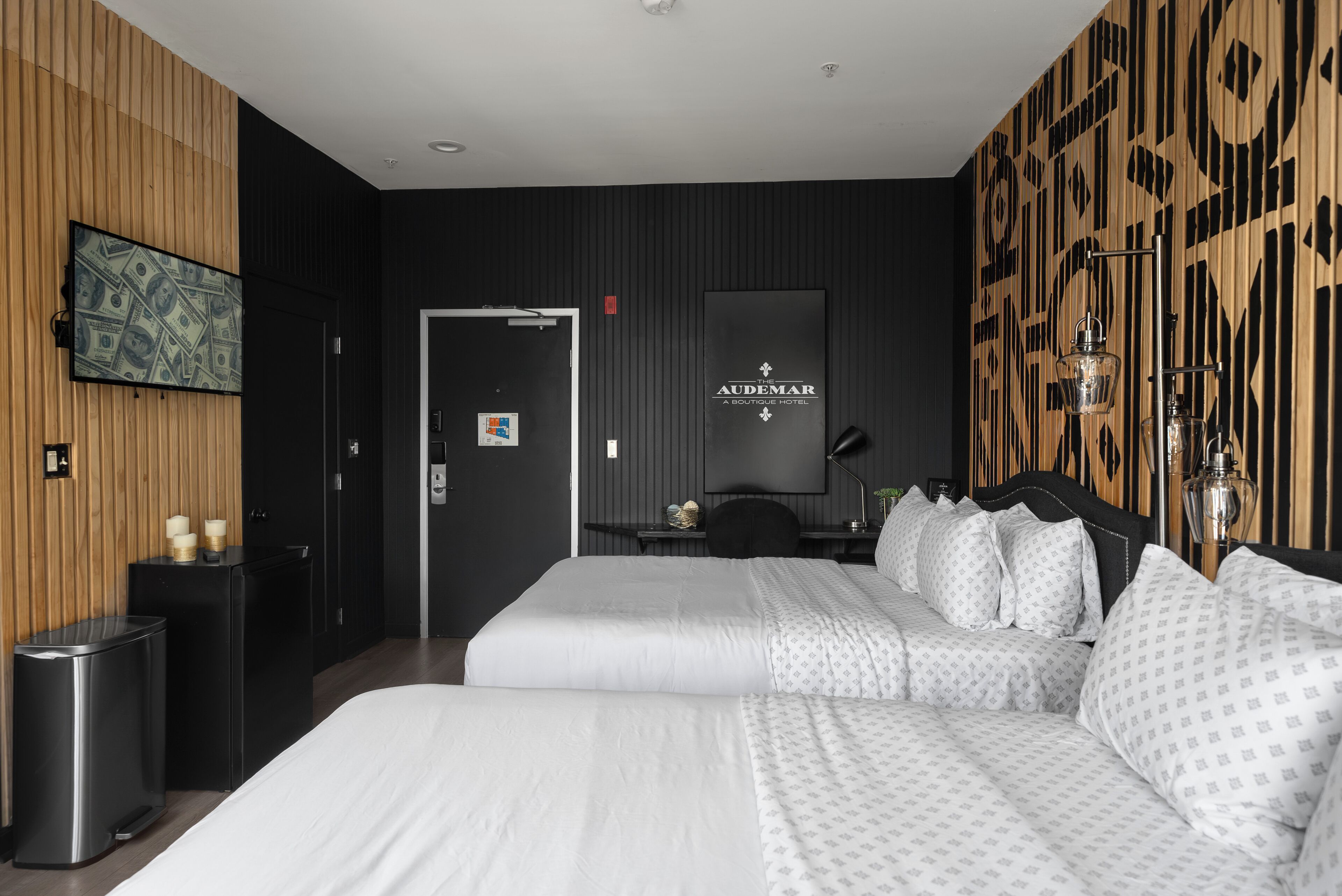 A hotel room with a large bed, a TV on the wall, a minibar, and a wooden accent wall.