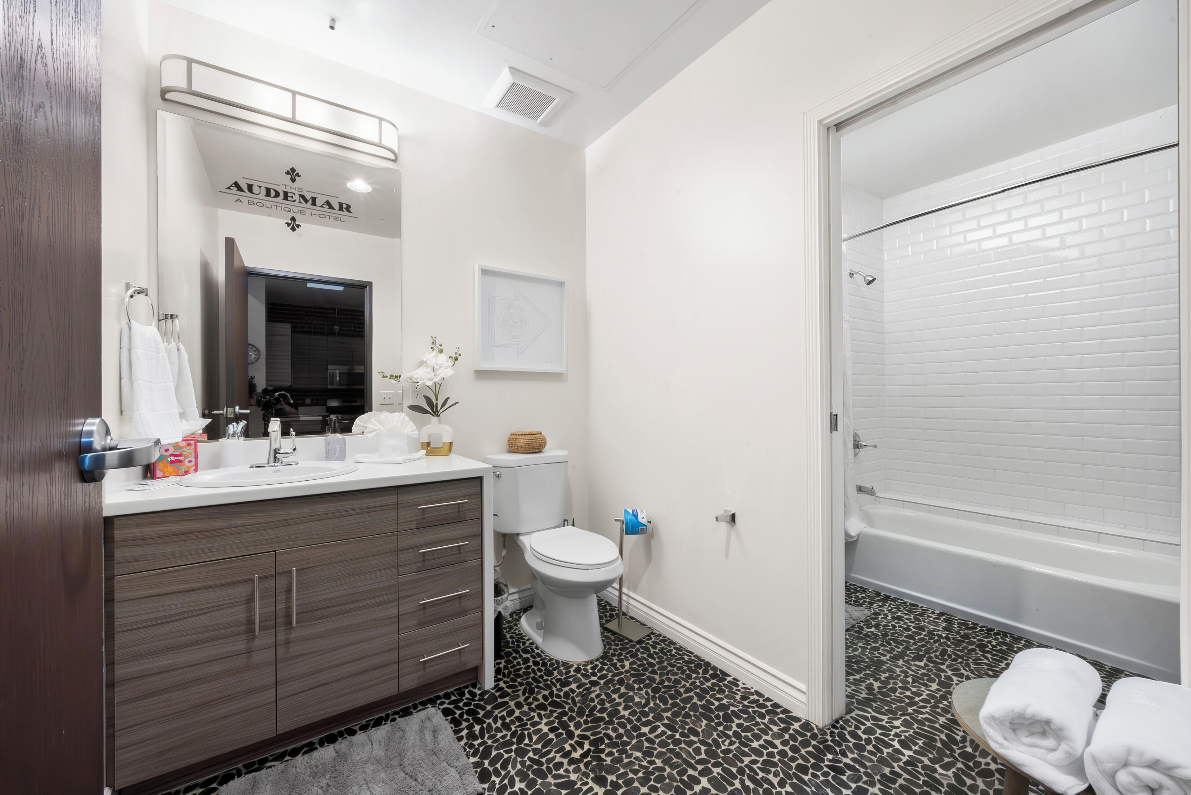 A modern bathroom with a white sink, dark wooden vanity, a toilet, and a white bathtub.