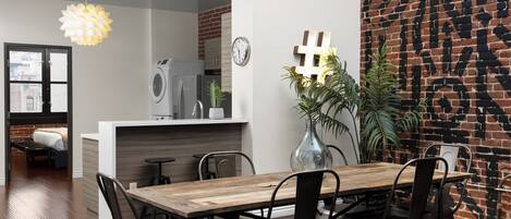 A modern kitchen with a wooden countertop, a built-in washing machine, and a hanging light fixture.